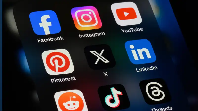 Smartphone home screen showing popular social apps: Facebook, Instagram, YouTube, Pinterest, X, LinkedIn, Reddit, TikTok, Threads.